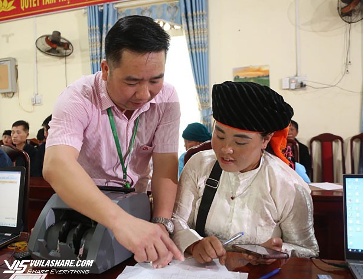 1-Giám đốc Ngân hàng Chính sách xã hội huyện Mèo Vạc Phùng Minh Thóc ân cần hướng dẫn cho đồng bào vay vốn Ảnh: NHCSXH